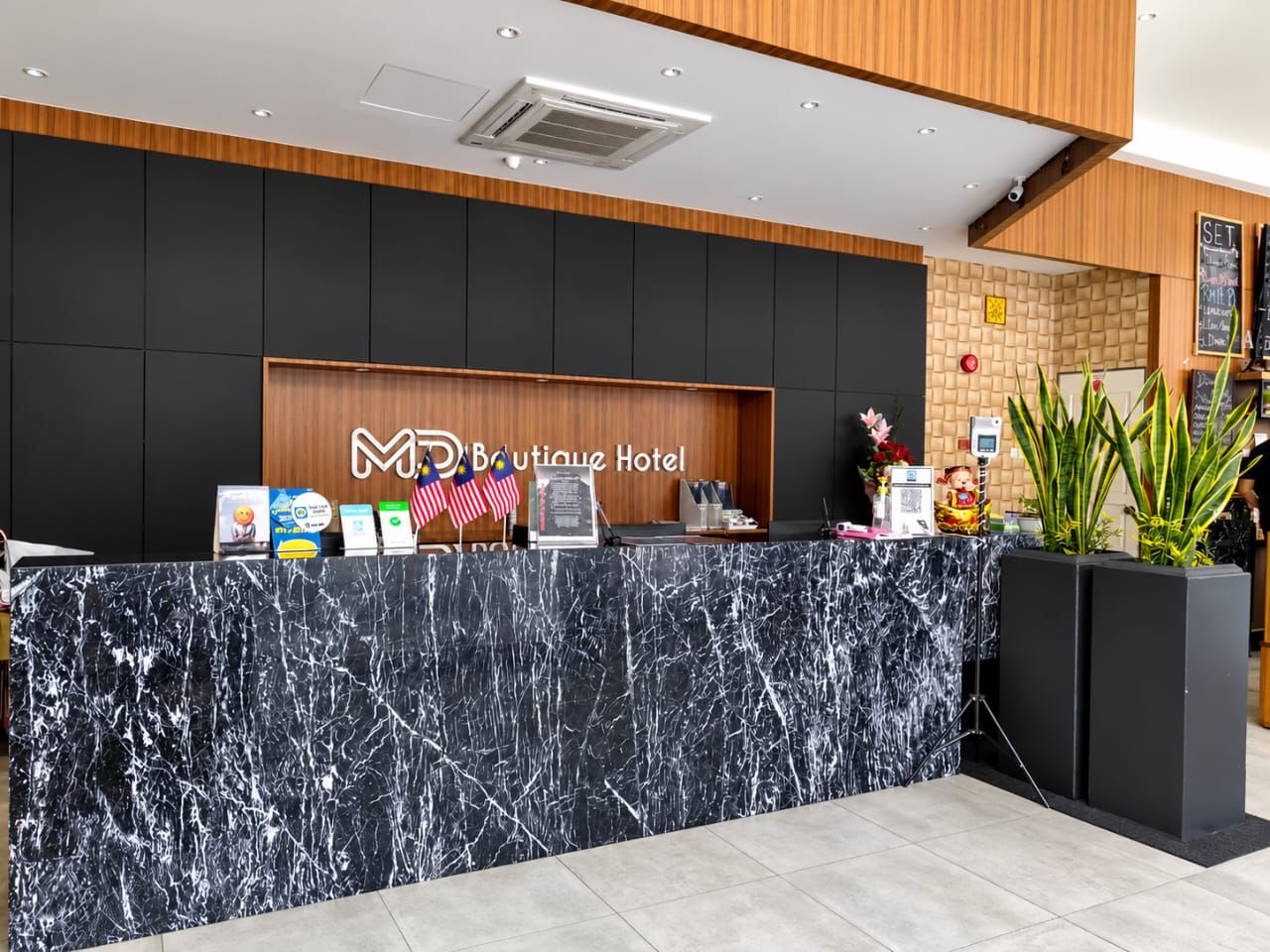 Reception desk in black marble with the MD Boutique Hotel sign on timber panelling